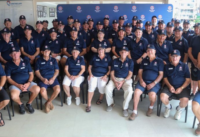 Group photo of Surf Life Saving NSW Life Members wearing navy uniforms and caps, seated and standing indoors.